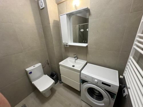 a bathroom with a toilet and a sink and a washing machine at Apartament Meraki Resort&Spa in Năvodari