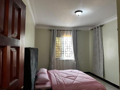 a bedroom with a bed in front of a window at El SALI APARTMENTS in Buwate