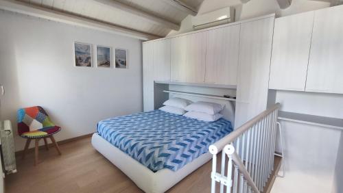 a small bedroom with a bed and a chair at Lagunahome Beatrice in Chioggia
