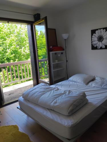 a bed in a bedroom with a large window at Appartement près du centre in Cahors