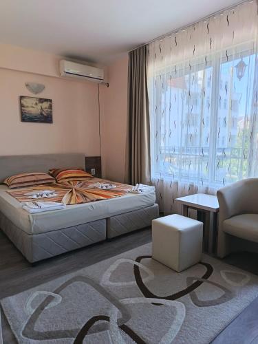a bedroom with a bed and a chair and a window at Fits Guest House in Primorsko