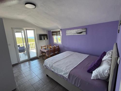 a bedroom with purple walls and a bed and a table at Apartmani Suzanna, apartman a in Eraci