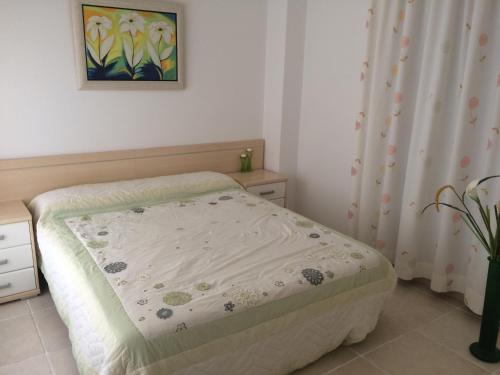 a small bedroom with a bed and a curtain at Apartamento La Tramuntana in Benidorm