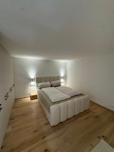 a white bedroom with a white bed and wooden floors at Casa Souterrain in Immenstaad am Bodensee