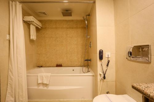 a bathroom with a tub and a toilet and a phone at Atithi Resort & Spa in Pokhara
