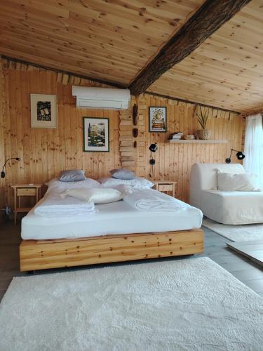 a large bed in a room with wooden walls at Lombfészek in Rezi