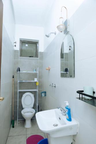 a white bathroom with a toilet and a sink at MtaaLiving-Bamburi in Mombasa