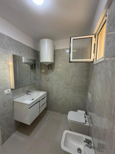a bathroom with a sink and a toilet and a mirror at Arkej Pool Aparthotel in Golem