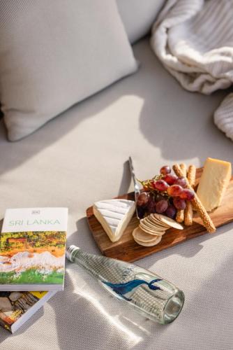 a tray of cheese and crackers and a book on a bed at Amadiya Port Arthur Villas in Port Arthur