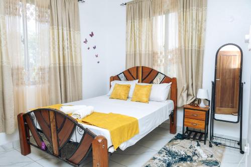 a bedroom with a bed with a yellow blanket on it at MtaaLiving-Bamburi in Mombasa