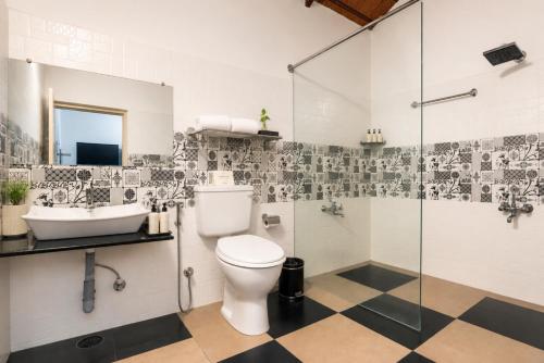 a bathroom with a toilet and a sink and a shower at The Blossom Resort - Chikmagalur in Chikmagalūr