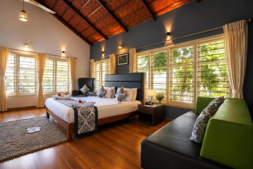 a bedroom with a bed and a couch and windows at The Blossom Resort - Chikmagalur in Chikmagalūr