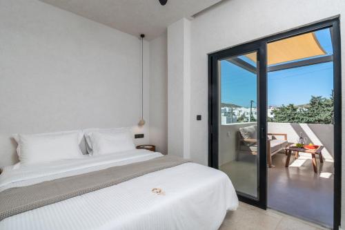a white bedroom with a bed and a balcony at Ostria Vento in Pollonia