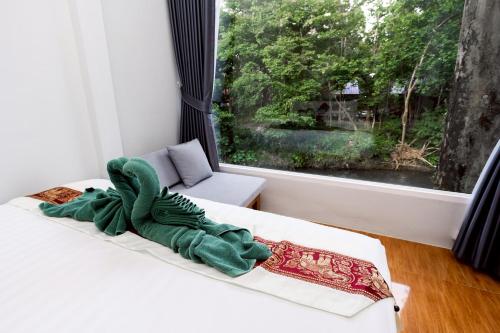 a stuffed animal sitting on a bed in front of a window at Khao Sok Jungle Huts Resort in Khao Sok National Park