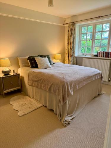 a bedroom with a large bed and a window at Recently renovated Lodge Cottage, Quantocks in West Bagborough