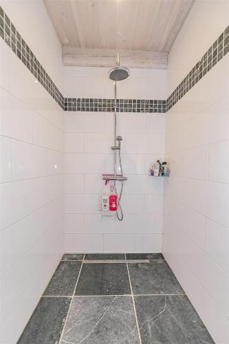 a bathroom with a shower with white tiled walls at d'Oude Smidse in Zuienkerke