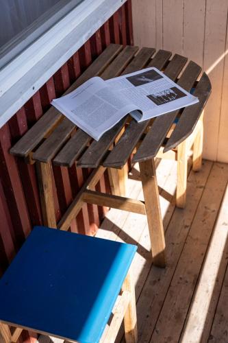 eine Holzbank mit einem Tisch und einer Zeitung darauf in der Unterkunft Zunda in Nida