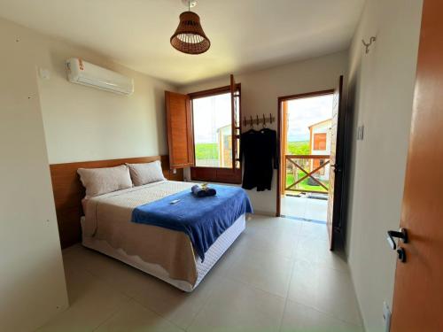 a bedroom with a bed with a blue blanket on it at Chalé Átina - Atins in Atins