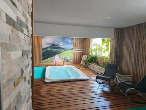 a room with a hot tub on a wooden deck at Maison Legate "Hôtel Le Baudiere & Spa" in Saint-Beauzire