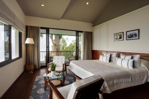 a bedroom with a large bed and a living room at Singell Tea Estate - A CGH Earth Experience in Darjeeling