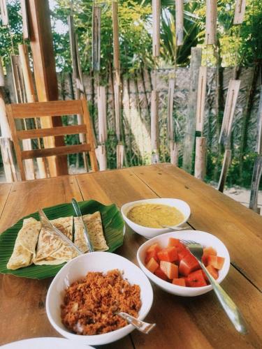 a wooden table with three bowls of food on it at Borassus Nature Huts by ABC Leisure's group in Jaffna