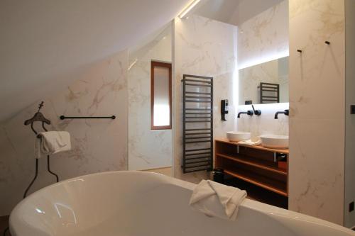 a bathroom with a bath tub and a sink at Logis Hotel Domaine de Rouffach in Rouffach