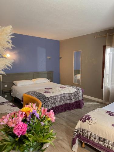 a hotel room with two beds and flowers on the floor at Maison Legate "Hôtel Le Baudiere & Spa" in Saint-Beauzire