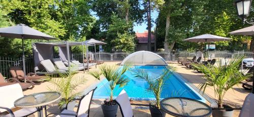 a swimming pool with tables and chairs and umbrellas at Doris Hotel in Siófok