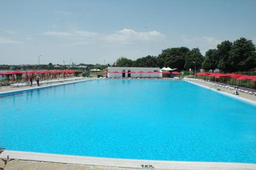 a large blue swimming pool with red umbrellas at Apartament Eduard in Techirghiol