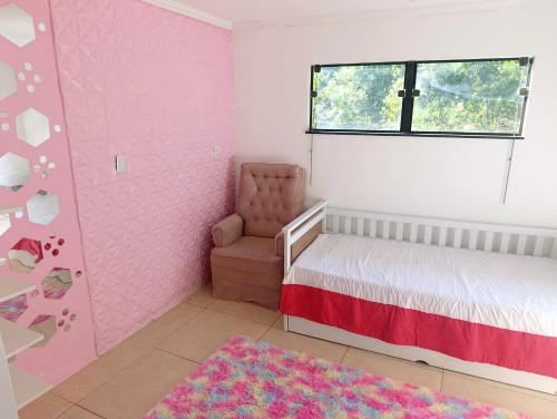 a pink bedroom with a bed and a chair at Linda Chácara Próxima a Monte Verde in Camanducaia