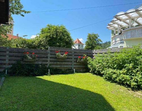 a wooden fence with red flowers in a yard at Apartma BONUS in Begunje na Gorenjskem