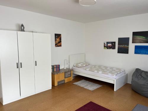 a white room with a bed and a cabinet at Ferienhaus im Grünen in Weimar