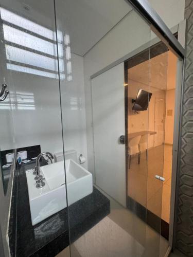 ein Badezimmer mit Waschbecken und Glasdusche in der Unterkunft Hotel Picpo in Ponte Nova