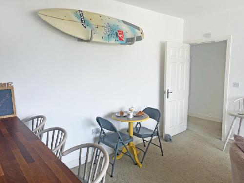 a surfboard hanging on a wall next to a table and chairs at 6 Pentire Mews in Newquay