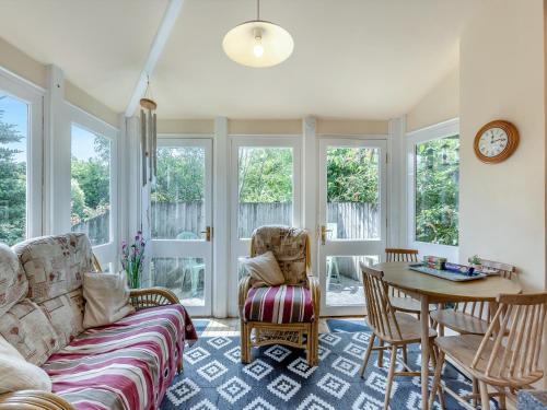 ein Wohnzimmer mit Sofa, Tisch und Fenstern in der Unterkunft Primula House in Sticklepath