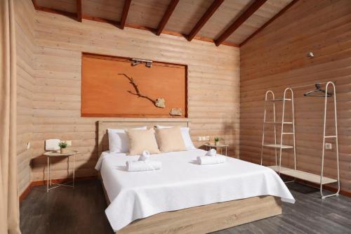 a bedroom with a white bed in a wooden wall at Hilltop Chalet 4 in Hanioti