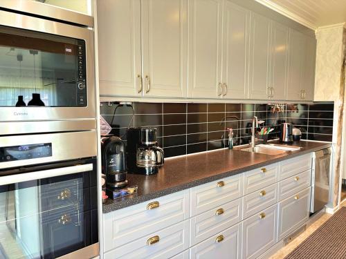 a kitchen with white cabinets and a sink at Villa Dångebo in Tingsryd
