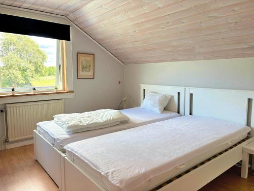 a bedroom with a large white bed with a window at Villa Dångebo in Tingsryd
