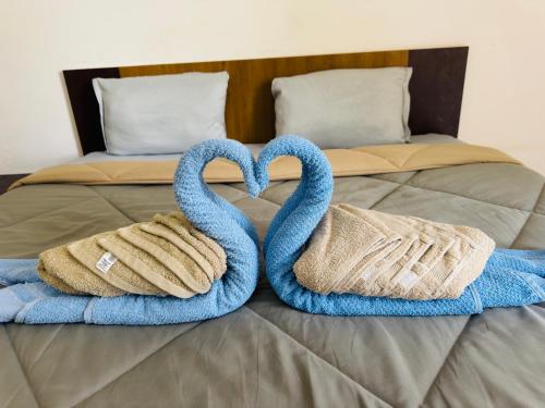 two towel swans sitting on top of a bed at manoj lodge in Sangamner
