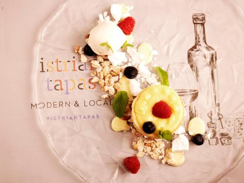 a plate with fruit and ice cream and a bottle of wine at Wellness Hotel Apollo – Terme & Wellness LifeClass in Portorož