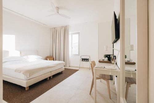 a white bedroom with a bed and a desk at Ritrovare Country House in Citta' Sant'Angelo