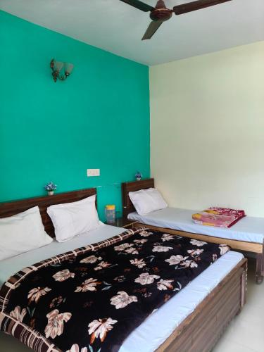 two beds in a room with a green wall at Hotel B M AND SONS in Phata