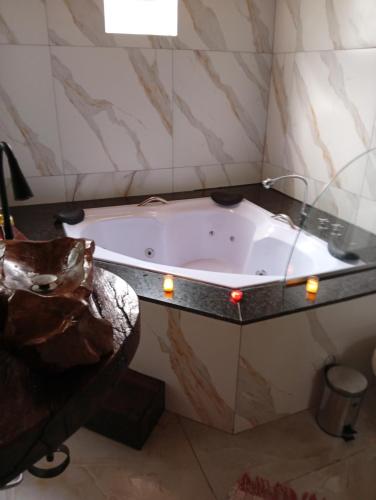 a bath tub in a bathroom with a glass wall at Pousada Canto do Sossego in Brumadinho