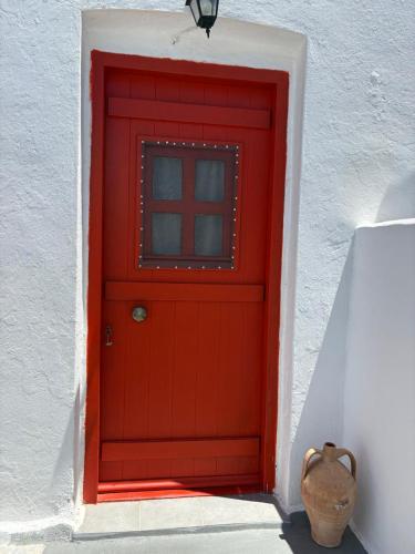 a red door with a window on a white wall at Venduri House in Péran Triovasálos