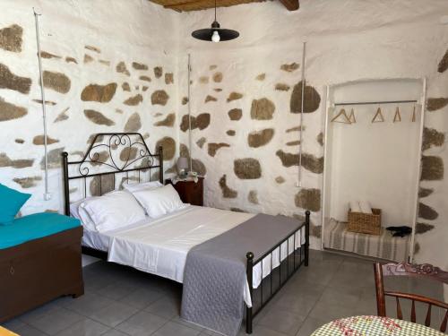 a bedroom with a bed and a stone wall at Venduri House in Péran Triovasálos