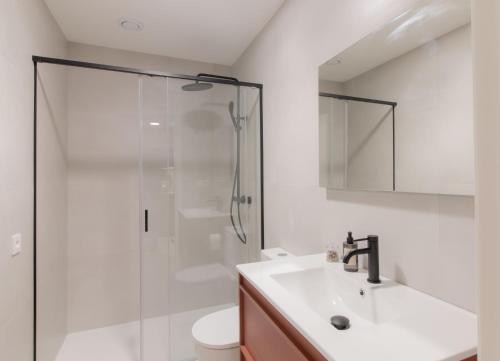 a white bathroom with a shower and a sink at Apartamentos Turísticos A Mariña Do Carril in Vilagarcia de Arousa