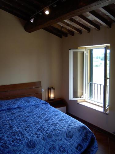 a bedroom with a blue bed and a window at B&B La Corte in Capannori