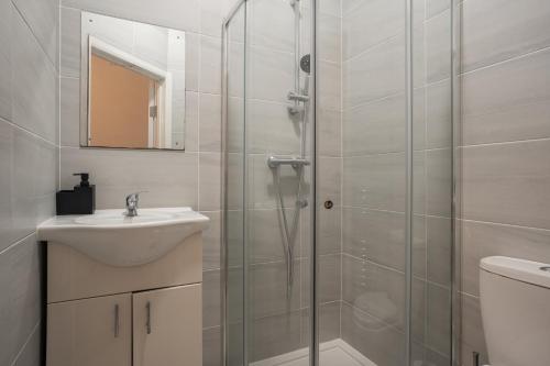 a bathroom with a shower with a sink and a toilet at Modern 3 Bed Flat - 3 En-Suites - Parking - near Wembley in Edgware