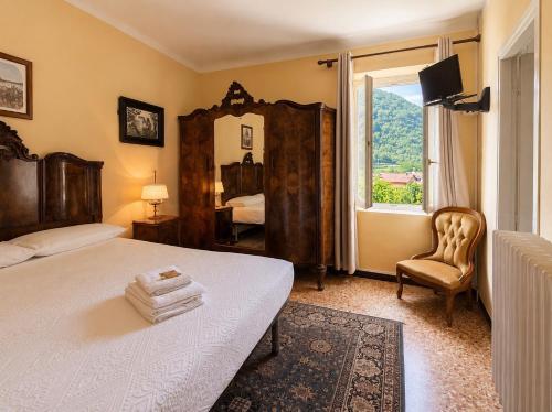 a bedroom with a bed and a mirror and a chair at Albergo dell'Angelo in Pieve di Teco