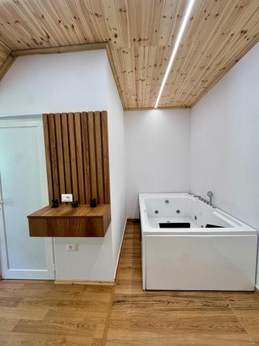 a bath tub in a room with a wooden ceiling at Old Mill Heritage Hotel in Ndërlysaj